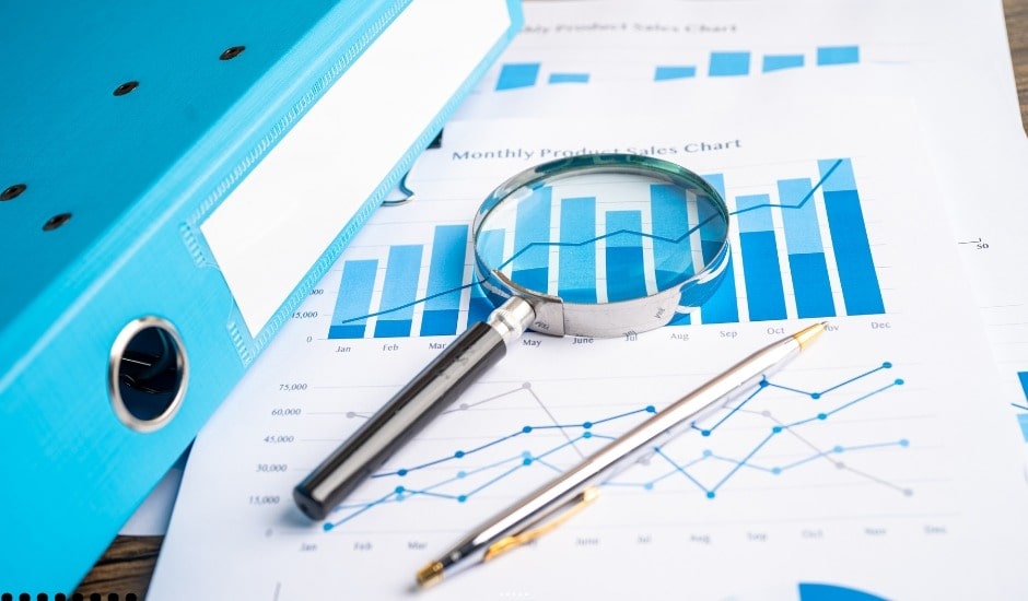 "Magnifying glass and charts used for market analysis showing financial trends and data insights."